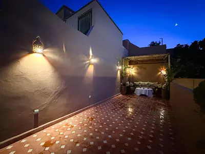 a patio with a table and lights on a building at Riad M Azbetz in Marrakech