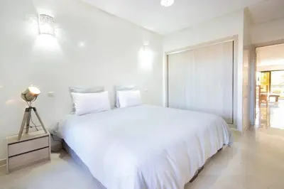a white bedroom with a large bed and a window at Sumptuous appart Heart of Hivernage - Pool in Marrakech