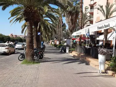 a sidewalk with palm trees and motorcycles on a street at Super cosy fully equip - pool - prox. M Avenue in Marrakech