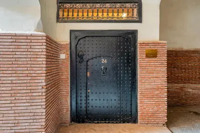 a black metal door in a brick wall at Riad Akasia in Marrakech