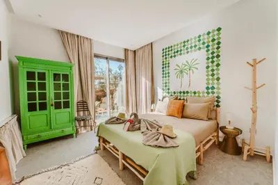 a bedroom with two beds and a green door at Villa - Piscine chauffée sur demande et gouvernante in Marrakech