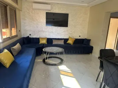 a living room with a blue couch and a table at Jardin Majorel Appartement en résidence fermée in Marrakech