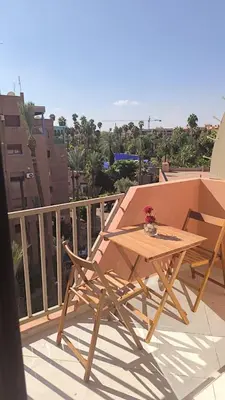 a wooden table and two chairs on a balcony at Jardin Majorel Appartement en résidence fermée in Marrakech