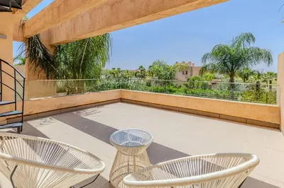a patio with chairs and a large window at Villa sur golf avec piscine privée chauffée in Marrakech