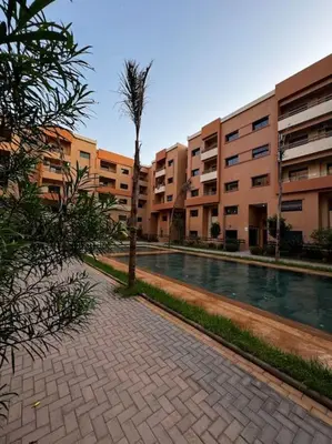a courtyard with a palm tree in front of a building at Appartement confort in Marrakech