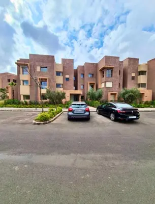 two cars parked in a parking lot in front of a building at Appartement de vacances à Prestigia golf city rez jardin in Marrakech