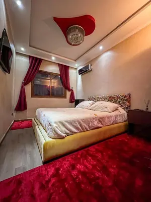 a bedroom with a bed and a red rug at Superbe Appartement en Résidence, Marrakech Guiliz in Marrakech