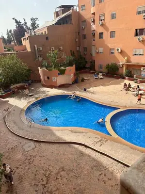 two swimming pools in a courtyard with buildings at Superbe Appartement en Résidence, Marrakech Guiliz in Marrakech