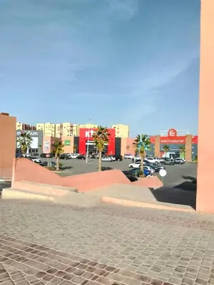 a city street with palm trees and a parking lot at Cozy Apartment in Hay Charaf district, Marrakech in Marrakech