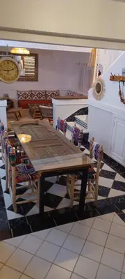 a wooden table and chairs in a room with a clock at Riad Kechin Beldi in Marrakech