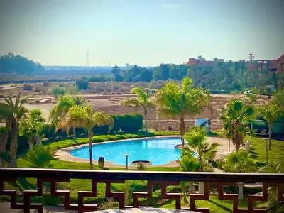 a swimming pool in a field with palm trees at cozy appartement in Marrakech