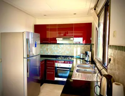 a kitchen with red cabinets and a stainless steel refrigerator at cozy appartement in Marrakech