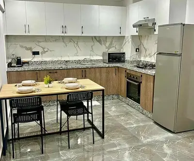 a kitchen with a table with chairs and a refrigerator at La Palmeraie Luxueux avec Piscine et Parking in Marrakech