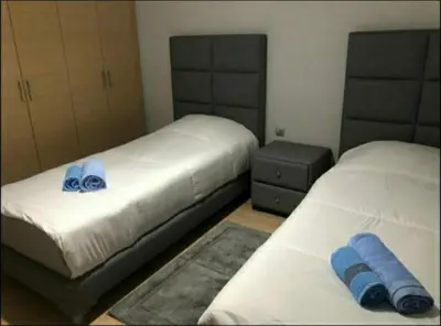two beds in a bedroom with blue pillows on them at Prestigia appartement in Marrakech