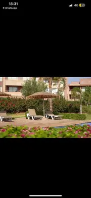 two chairs and an umbrella in a park at Appartement Marrakech prestigia by Sofia 2 chambres piscine in Marrakech