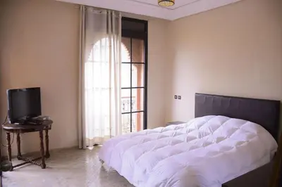 a bedroom with a large white bed and a television at Capstay Riad Villa in secure residence in Marrakech