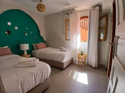a bedroom with two beds and a green wall at Appartement Palmeraie avec terrasse in Marrakech