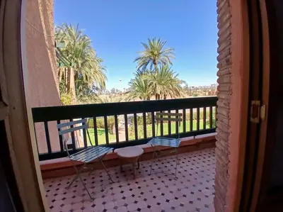 a balcony with two chairs and palm trees in the background at Appartement Palmeraie avec terrasse in Marrakech