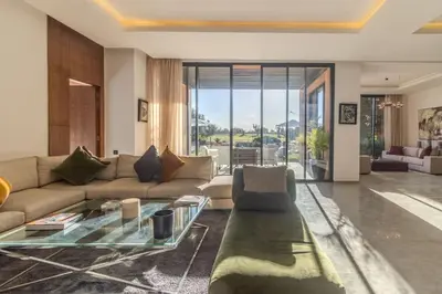a living room with a couch and a glass table at HM50 l Villa en front de golf piscine & jacuzzi in Marrakech