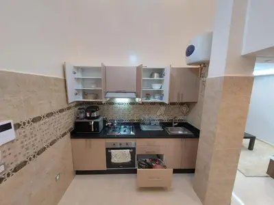 a small kitchen with brown cabinets and appliances at Duplex tres beau avec wifi in Marrakech