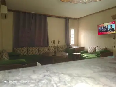 a living room with green couches and a tv at Au cœur de Marrakech in Marrakech