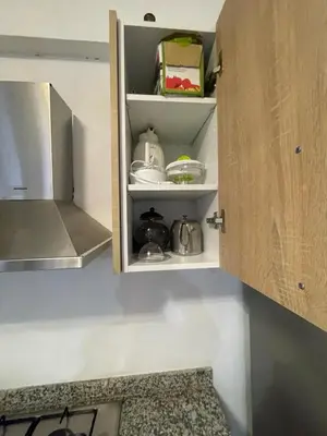 a kitchen cupboard with some dishes on it at Appartement bien équipé in Marrakech