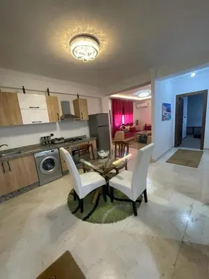 a kitchen and living room with a table and chairs at Appartement bien équipé in Marrakech
