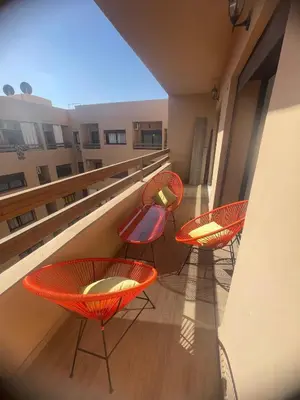 a balcony with four chairs and tables on a building at Appartement bien équipé in Marrakech