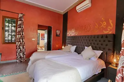 two beds in a bedroom with orange walls at Villa Sahar in Marrakech