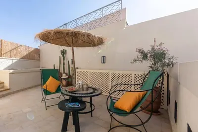 a patio with chairs and a table and an umbrella at Riad BAB 19 in Marrakech