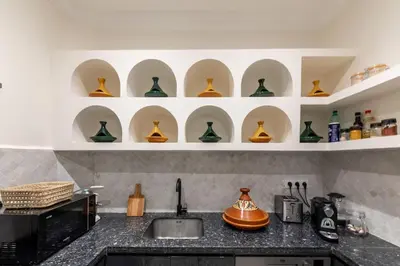 a kitchen with a sink and shelves of vases at Riad BAB 19 in Marrakech