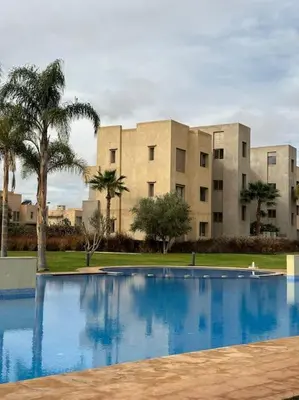 a swimming pool in front of a building with palm trees at Jubaea youmna in Marrakech