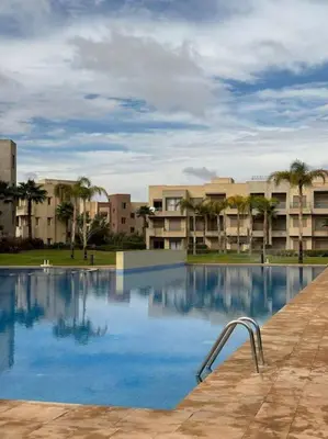 a swimming pool with a metal handrail in front of a building at Jubaea youmna in Marrakech