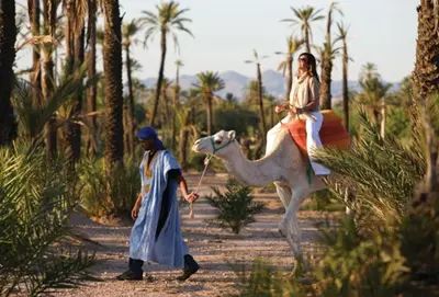 a woman riding a camel with a man riding a camel at NATURALapartmentLARGE pool in Marrakech