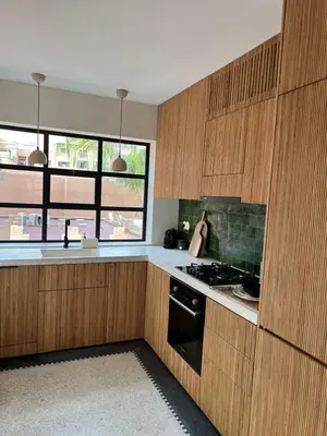 a kitchen with wooden cabinets and a stove top oven at Appartement Élégant et Spacieux Près de Carré Eden in Marrakech
