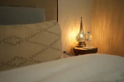 a bed with a lamp and a bottle on a night stand at Romantic getaway heart of Gueliz in Marrakech