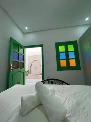 a bedroom with a bed and colorful windows at Gîte Familial Aïcha in El Gouassem