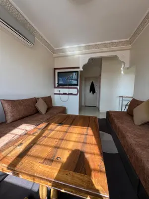 a living room with a wooden table and a couch at Location Familiale Marrakech 2 in Marrakech