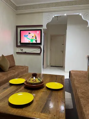 a living room with a wooden table with yellow plates on it at Location Familiale Marrakech 2 in Marrakech