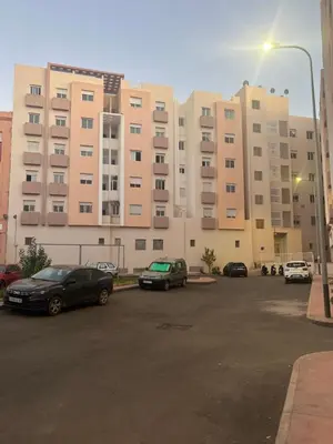 a parking lot with cars parked in front of a large building at Superbe appartement à Marrakech in Marrakech