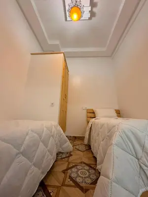 a bedroom with two beds and a light on the ceiling at cosy appartement a marrakech in Marrakech