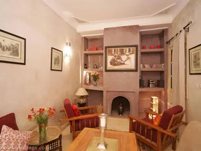 a living room with a table and a fireplace at Riad Lou Kasbah in Marrakech
