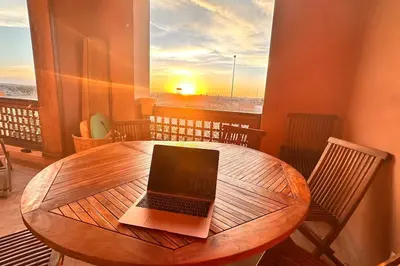 a laptop computer sitting on a wooden table on a balcony at Marrakech flat with swimming pool & sunny garden in Marrakech
