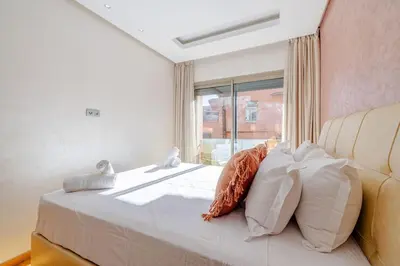 a bedroom with a bed with pillows and a window at Best location new appart café de la poste Plaza in Marrakech