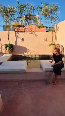 a woman sitting on a bench in front of a fountain at Le RIAD Paradis Secret in Marrakech