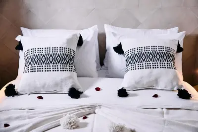 a white bed with white pillows and flowers on it at Riad Tawkane in Marrakech