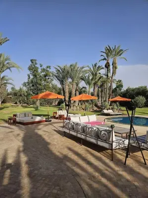 a resort with a pool and tables and umbrellas at Villa jowehara Palmeraie Marrakech in Marrakech