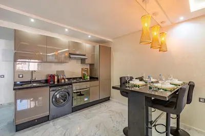 a kitchen with a table and a washer and dryer at Charm Apt dans le triangle Tourisme de Marrakech ! in Marrakech