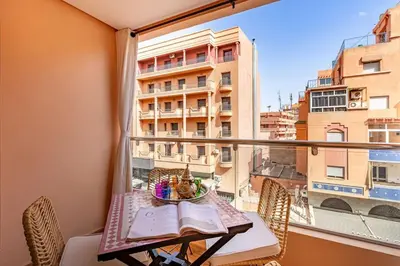 a balcony with a table and a view of a building at Charm Apt dans le triangle Tourisme de Marrakech ! in Marrakech