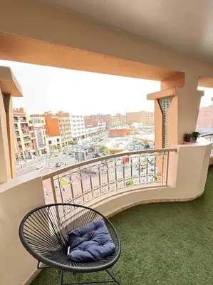 a chair on a balcony with a view of a city at Appart au Cœur de Gueliz in Marrakech
